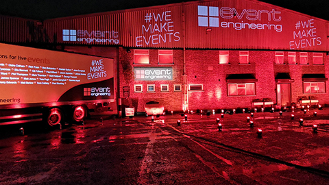 Photo of a warehouse and lorry taken in red light. The building is branded with 